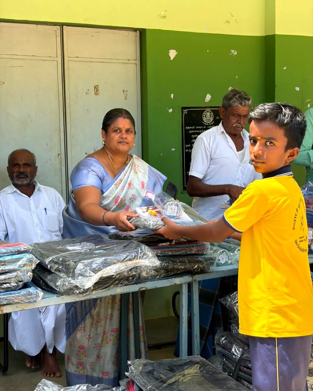 Notebooks being handed out to students at Govt. School, Kombukuttai